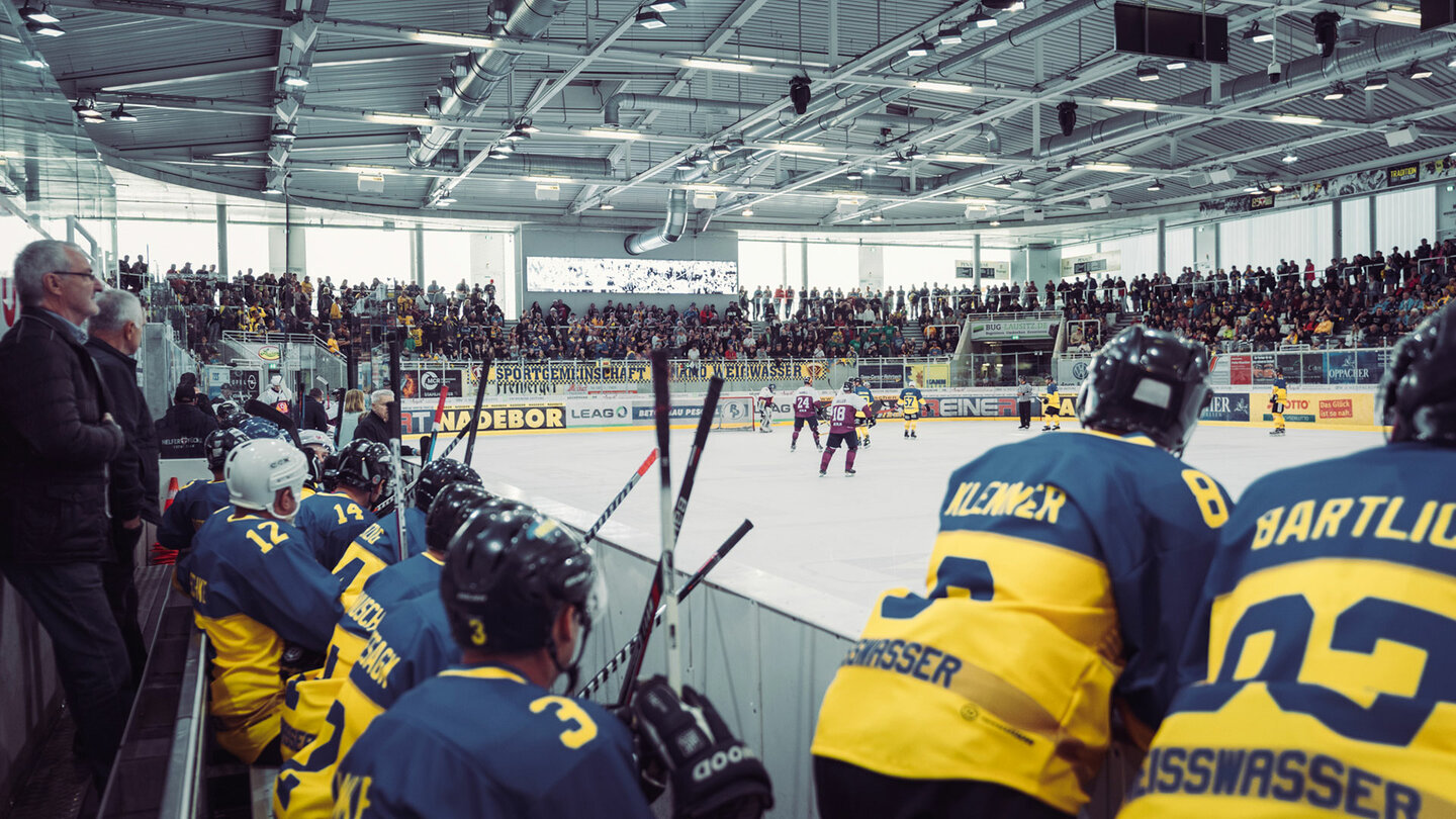 Foto von der Mannschaftsbank beim Spiel der Legenden mit Blick auf die Eishockeyfläche und Block D