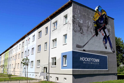 Gebäudekomplex mit gemaltem Eishockeyspieler an der Hauswand