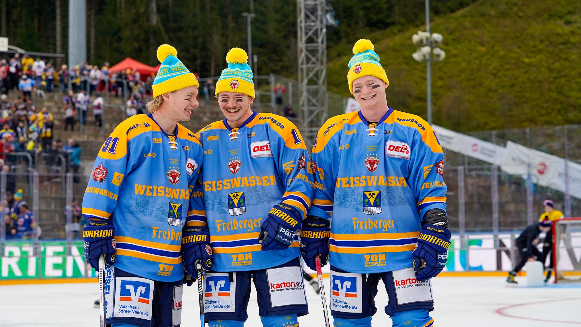 Roope Mäkitalo, Luis Anders und Kristian Blumenschein lächeln in die Kamera mit Trikot und Mützen